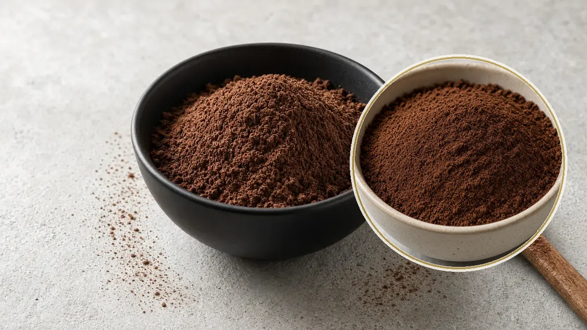 Tazón negro con cocoa en polvo fino y una cuchara de madera sobre una barra de concreto gris.
