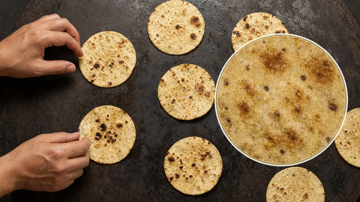 Persona levantando una tortilla del comal. En primer plano, la pila de tortillas.
